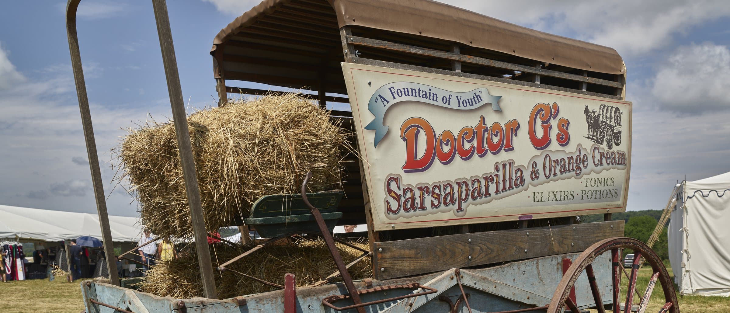 A painted travelling medicine wagon whose sign reads “A Fountain of Youth — Doctor G’s Sarsaparilla and Orange Cream, Tonics, Elixirs, Potions”